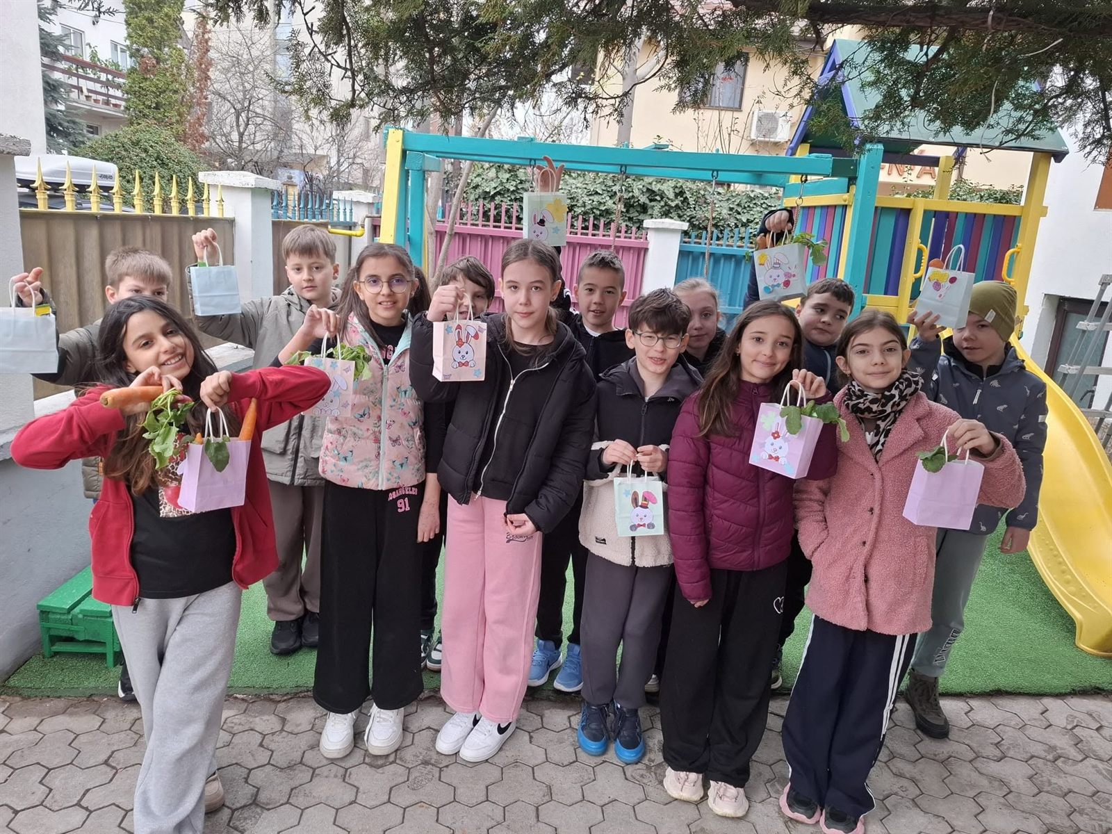 Copii în curtea de joacă a clubului, cu ansamblul din lemn în spate